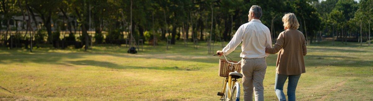 pareja de adultos realizando actividad física al aire libre, con una bicicleta en la mano
