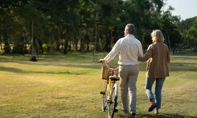 pareja de adultos realizando actividad física al aire libre, con una bicicleta en la mano