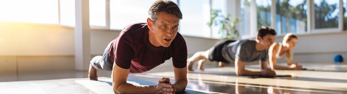 Adultos en posición de plancha, ejercitando su cuerpo
