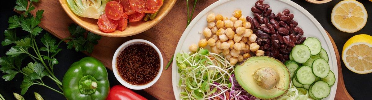 Mesa con alimentos saludables como: garbanzos, aguacate, almendras pepino, frijol, pimentón y más vegetales