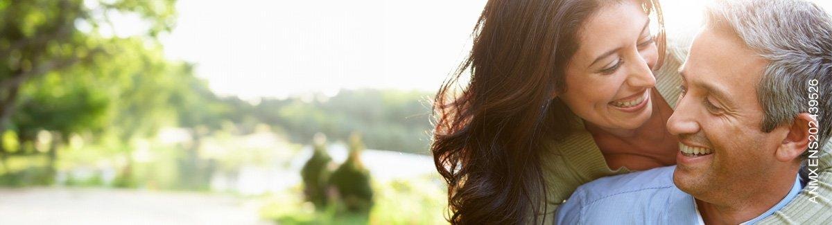 Pareja de adultos abrazados al aire libre, sonriendo