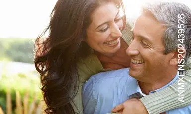 Pareja de adultos abrazados al aire libre, sonriendo