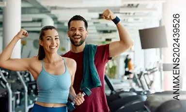Pareja de adultos en el gimnasio, sonriendo, enseñando sus músculo