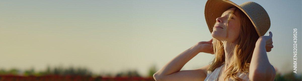 Mujer sonriendo mirando al sol, evocando estilo de vida saludable
