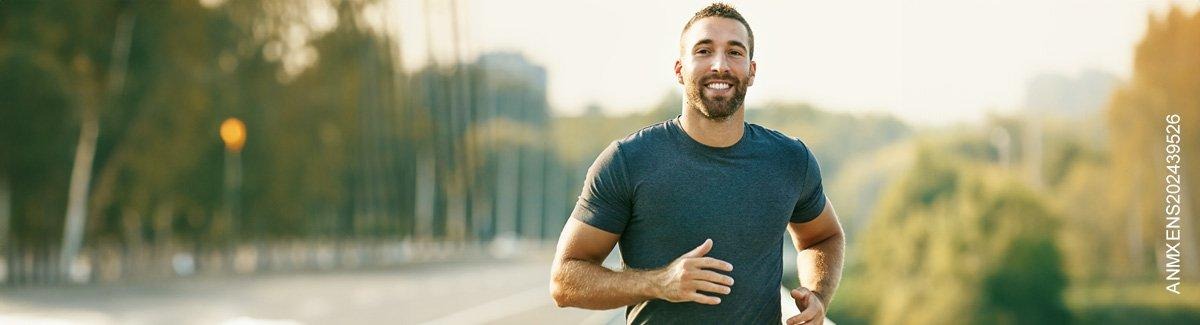 hombre trotando al aire libre, sonriendo en un día soleado