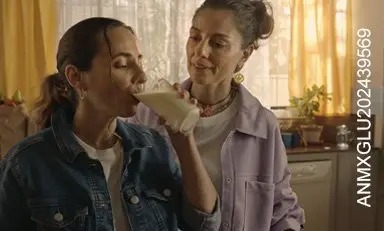 mujeres en la cocina, una está tomando una bebida y la otra la está observando con gesto de aprobación