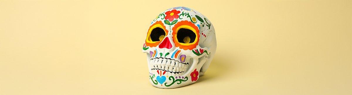 Configuración colorida con elementos típicos de un "Altar de Muertos". Hay una figurita de un esqueleto con un sombrero azul