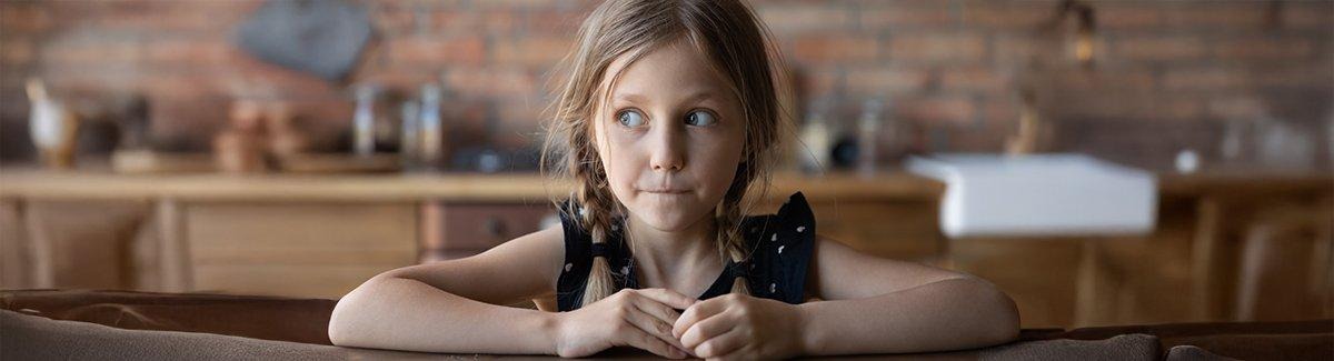 Niña sentada en el comedor mirando a su derecha