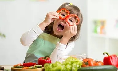 Niño con el rostro borroso, vistiendo un delantal y aparentemente preparando comida en un entorno de cocina.