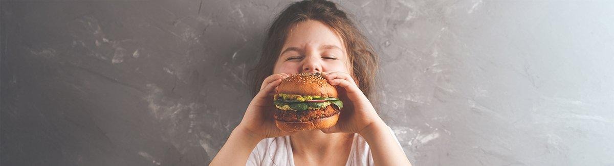 Niño mordiendo una hamburguesa