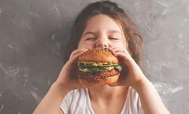 Niño mordiendo una hamburguesa