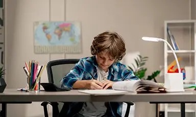Niño sentado en un escritorio haciendo sus deberes