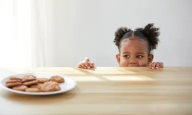 Niña observando galletas por encima de la mesa