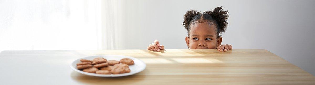 Niña observando galletas por encima de la mesa