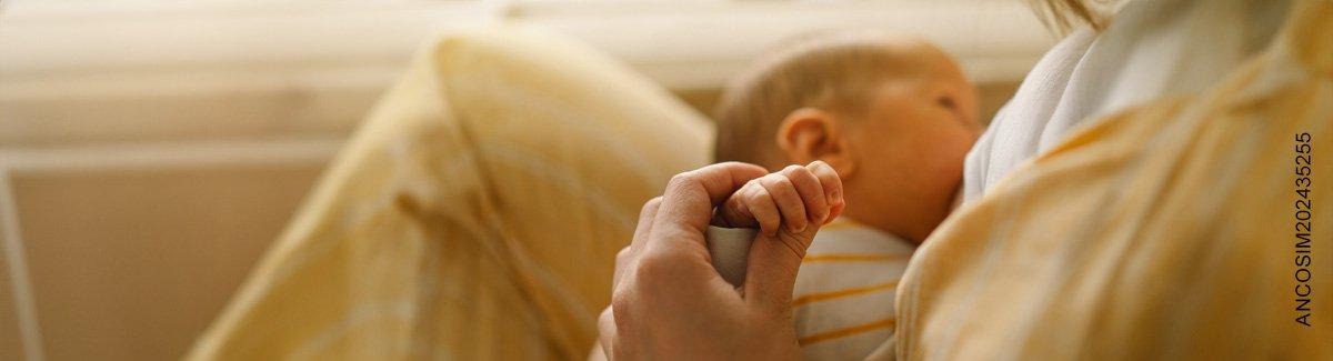 mamá amamanta a su bebé mientras sostiene su mano tiernamente