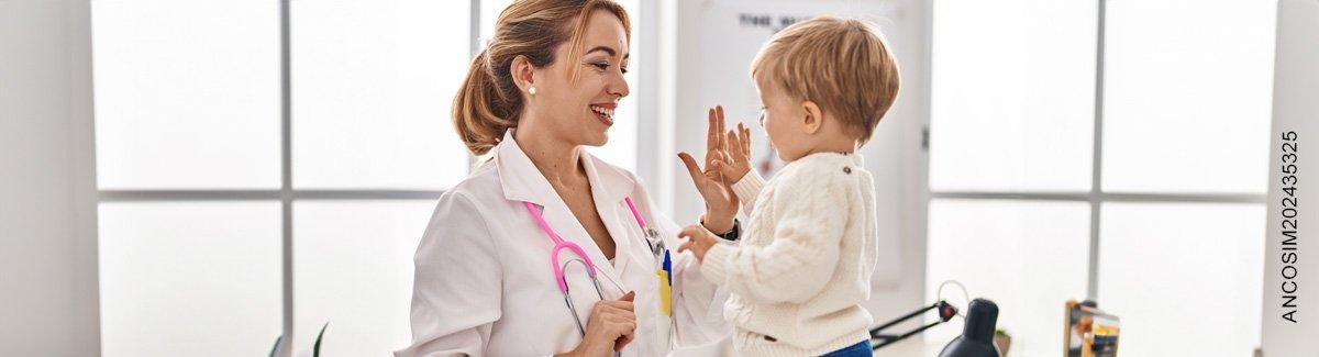  mujer pediatra choca las manos de manera amistosa con su pequeño paciente.