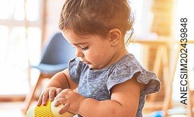 Niña de dos años con un juguete didáctico en sus manos en una habitación