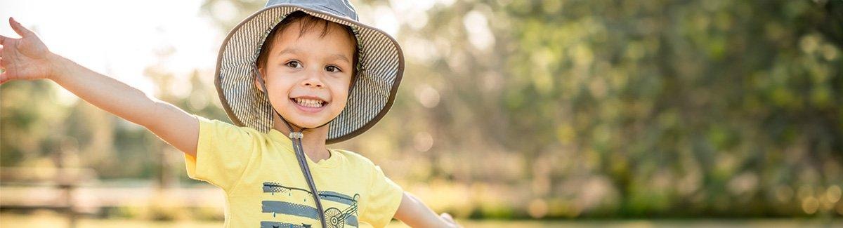 Niño sonriente con los brazos abiertos en la naturaleza