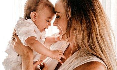 Mujer sostiene a su bebé frente a frente, sonriéndole