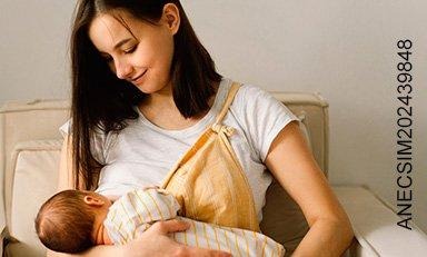 Mujer sonríe mientras amamanta a su bebé en una silla