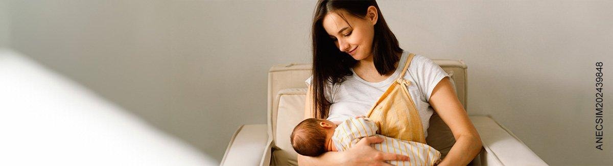 Mujer sonríe mientras amamanta a su bebé en una silla