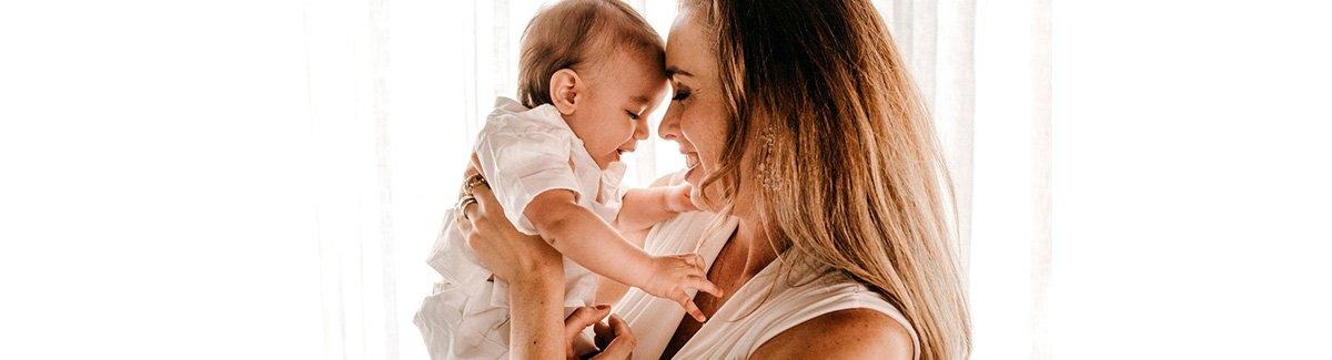 Mujer sostiene a su bebé frente a frente, sonriéndole