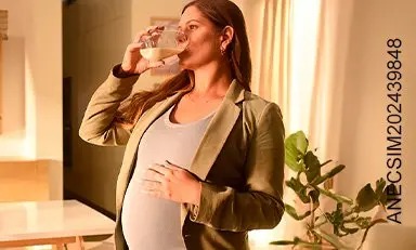 Mujer embarazada disfrutando de Similac® Mamá en hogar acogedor con luz natural