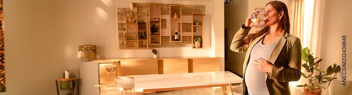 Mujer embarazada disfrutando de Similac® Mamá en hogar acogedor con luz natural