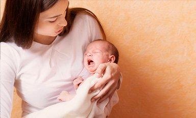 Mujer tiene a su hijo en sus brazos, el bebe está llorando