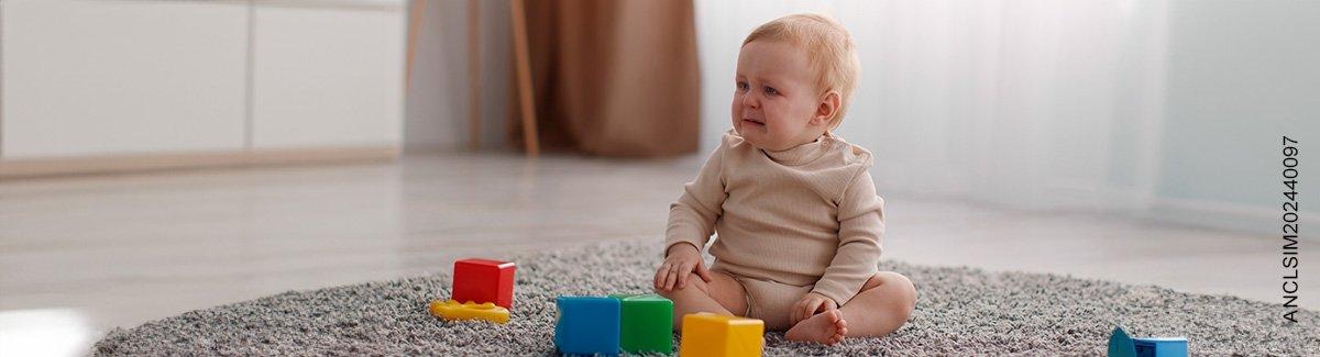 Bebe sentado en un tapete llorando