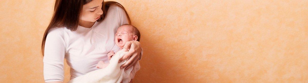 Mujer tiene a su hijo en sus brazos, el bebe está llorando