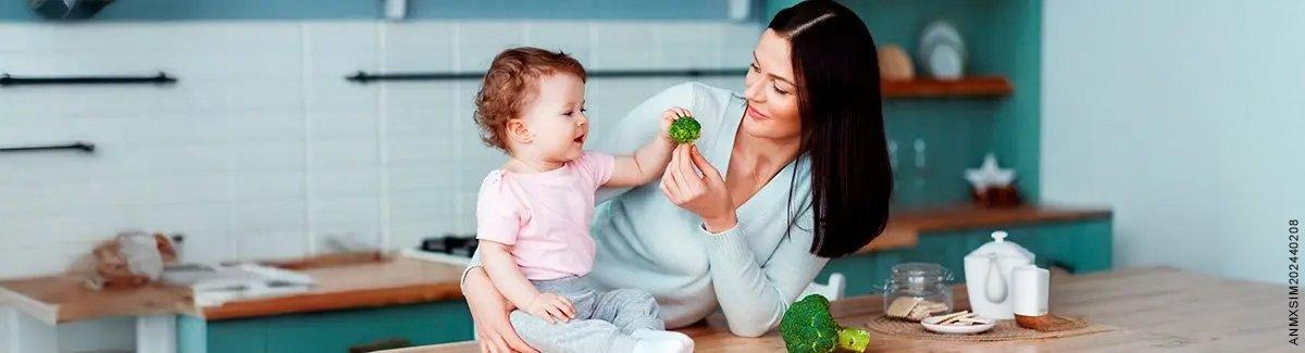 mamá dándole de comer a su hija pequeña alimentos saludables