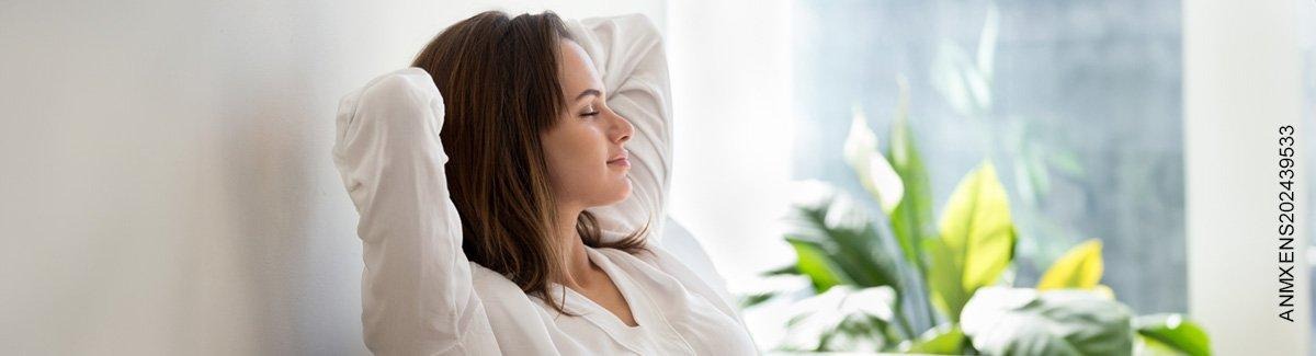 mujer con los ojos cerrados y las manos sobre la cabeza, con expresión de calma y descanso