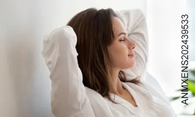 mujer con los ojos cerrados y las manos sobre la cabeza, con expresión de calma y descanso